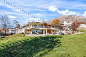 Back of house featuring a patio area, a chimney, a mountain view, and a balcony