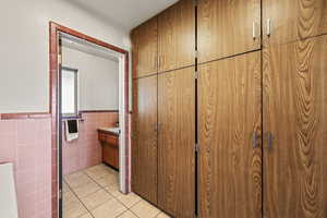 Bathroom featuring tile walls, a wainscoted wall, vanity, and light tile patterned floors