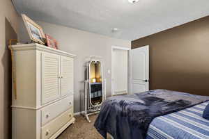 Bedroom featuring dark colored carpet and a textured ceiling