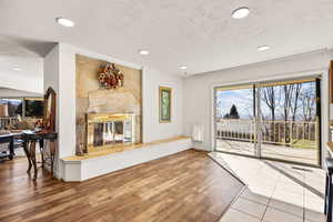 Living area featuring a premium fireplace, wood finished floors, healthy amount of natural light, recessed lighting, and a textured ceiling