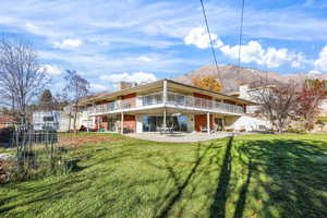 Back of property featuring a patio area, a chimney, a yard, a mountain view, and stairs
