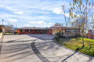 Ranch-style house with concrete driveway, brick siding, a front yard, and a garage