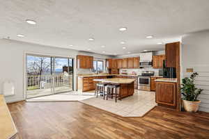 Kitchen featuring a breakfast bar, brown cabinetry, a kitchen island, stainless steel appliances, and light wood-style flooring