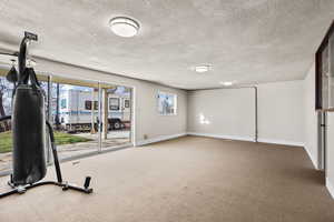 Workout area with a textured ceiling and light colored carpet