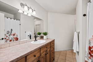 Bathroom featuring a shower with shower curtain, vanity, and light tile patterned flooring