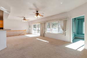 Carpeted empty room featuring a ceiling fan and baseboards