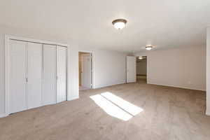 Unfurnished bedroom with light colored carpet and a closet