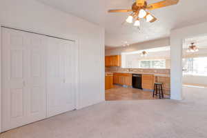 Kitchen with light countertops, light carpet, black dishwasher, brown cabinets, and decorative backsplash