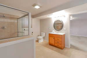 Full bath featuring tiled shower, light carpet, and vanity