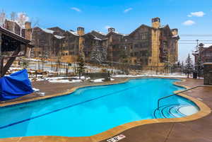 Snow covered pool featuring a community pool, a patio, and grilling area