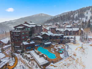 Snowy aerial view with view of pool area, a mountain view, and a residential view