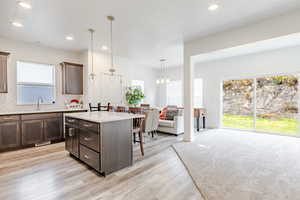 Kitchen featuring a kitchen island, backsplash, dark brown cabinets, decorative light fixtures, and recessed lighting