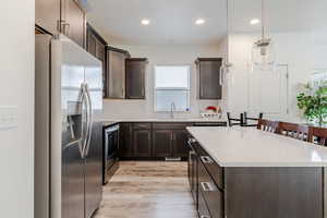 Kitchen with stainless steel appliances, dark brown cabinetry, a kitchen island, decorative backsplash, and recessed lighting
