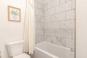 Bathroom with shower / bath combo with shower curtain and toilet