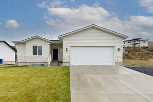 Single story home with concrete driveway, a front yard, and an attached garage