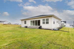 Rear view of property with a lawn and entry steps
