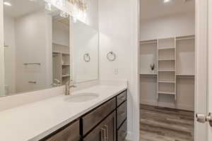 Full bath with a walk in closet, recessed lighting, vanity, and light wood-type flooring