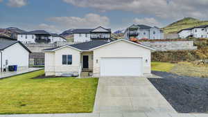 View of front of house featuring concrete driveway, a front lawn, and a mountain view