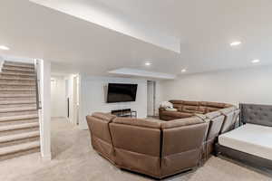 Living area with light colored carpet, recessed lighting, and stairs
