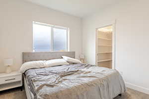 Bedroom with dark colored carpet and a spacious closet