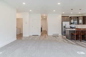Kitchen featuring dark brown cabinets, appliances with stainless steel finishes, recessed lighting, a breakfast bar, and decorative light fixtures