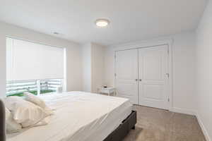 Bedroom with light colored carpet and a closet