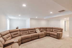 Living area with light carpet and recessed lighting
