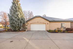 View of front of house with concrete driveway, stucco siding, an attached garage, and roof with shingles