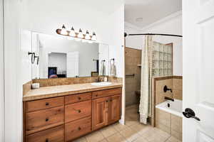 Full bathroom featuring vanity, crown molding, light tile patterned floors, ensuite bath, and tiled shower / bath