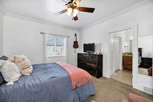 Tiled bedroom with carpet, crown molding, ceiling fan, and ensuite bathroom