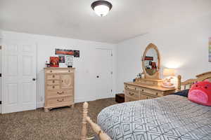 Bedroom with dark colored carpet and a textured ceiling