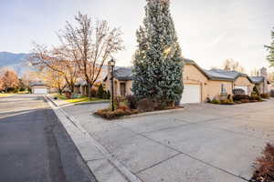 View of property hidden behind natural elements with a residential view, stucco siding, driveway, and a chimney