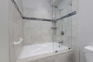 Bathroom featuring tiled shower / bath combo and toilet