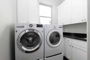 Washroom with washer and dryer and cabinet space and a sink