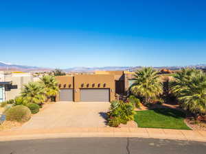 View of front of house with stucco siding, a garage, driveway, a mountain view, and a front yard