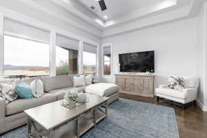 Living room featuring a tray ceiling, dark wood-style flooring, ceiling fan, and recessed lighting