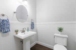 Half bath featuring wainscoting and dark wood finished floors
