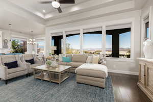 Living area featuring views of the mountains, a raised ceiling, a chandelier, dark wood-type flooring, recessed lighting, and a ceiling fan