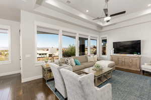 Living room featuring a raised ceiling, dark wood-type flooring, ceiling fan, and recessed lighting