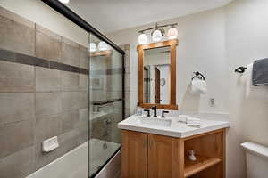 Full bath featuring shower / bath combination with glass door, vanity.