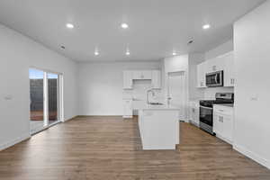 Kitchen featuring appliances with stainless steel finishes, white cabinets, recessed lighting, light wood-style floors, and a kitchen island with sink
