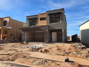 Contemporary house with stucco siding, stone siding, and a garage