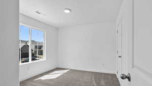 Spare room featuring carpet flooring and baseboards