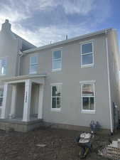 Rear view of property with stucco siding and covered porch