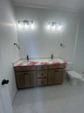 Full bathroom featuring double vanity and light marble finish flooring