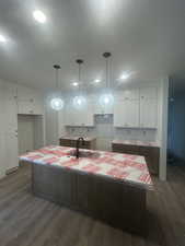 Kitchen featuring white cabinetry, hanging light fixtures, dark wood-type flooring, and recessed lighting