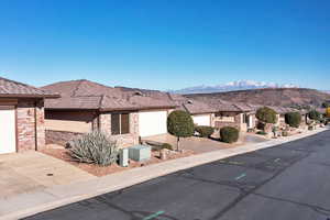 View of front of house with driveway, brick siding, stucco siding, a residential view, and a garage