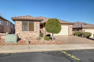 View of front facade with brick siding, driveway, and an attached garage