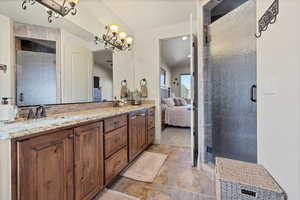 Ensuite bathroom featuring a stall shower, double vanity, decorative backsplash, and light stone finish floors