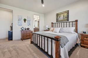 Bedroom featuring light carpet, ensuite bathroom, ceiling fan, recessed lighting, and a chandelier